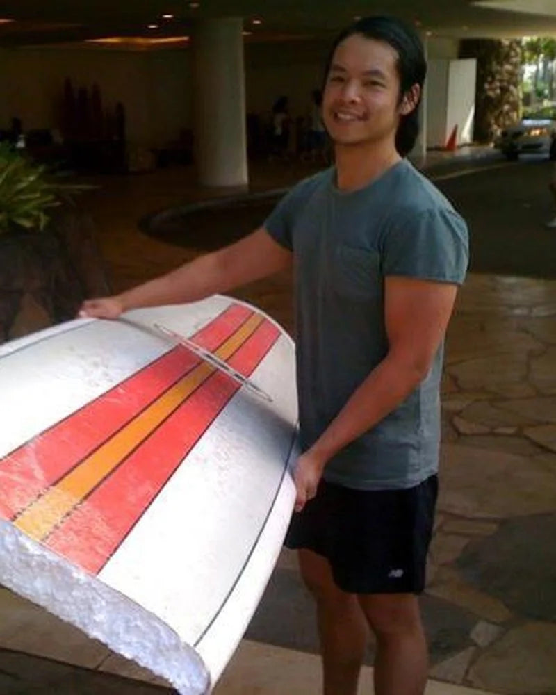 Van at 28 holding a foam surfboard