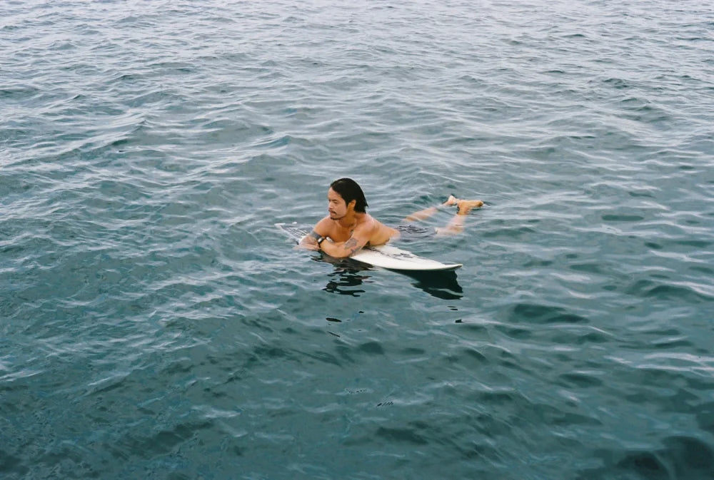 Van lying on his board in flat water after a session
